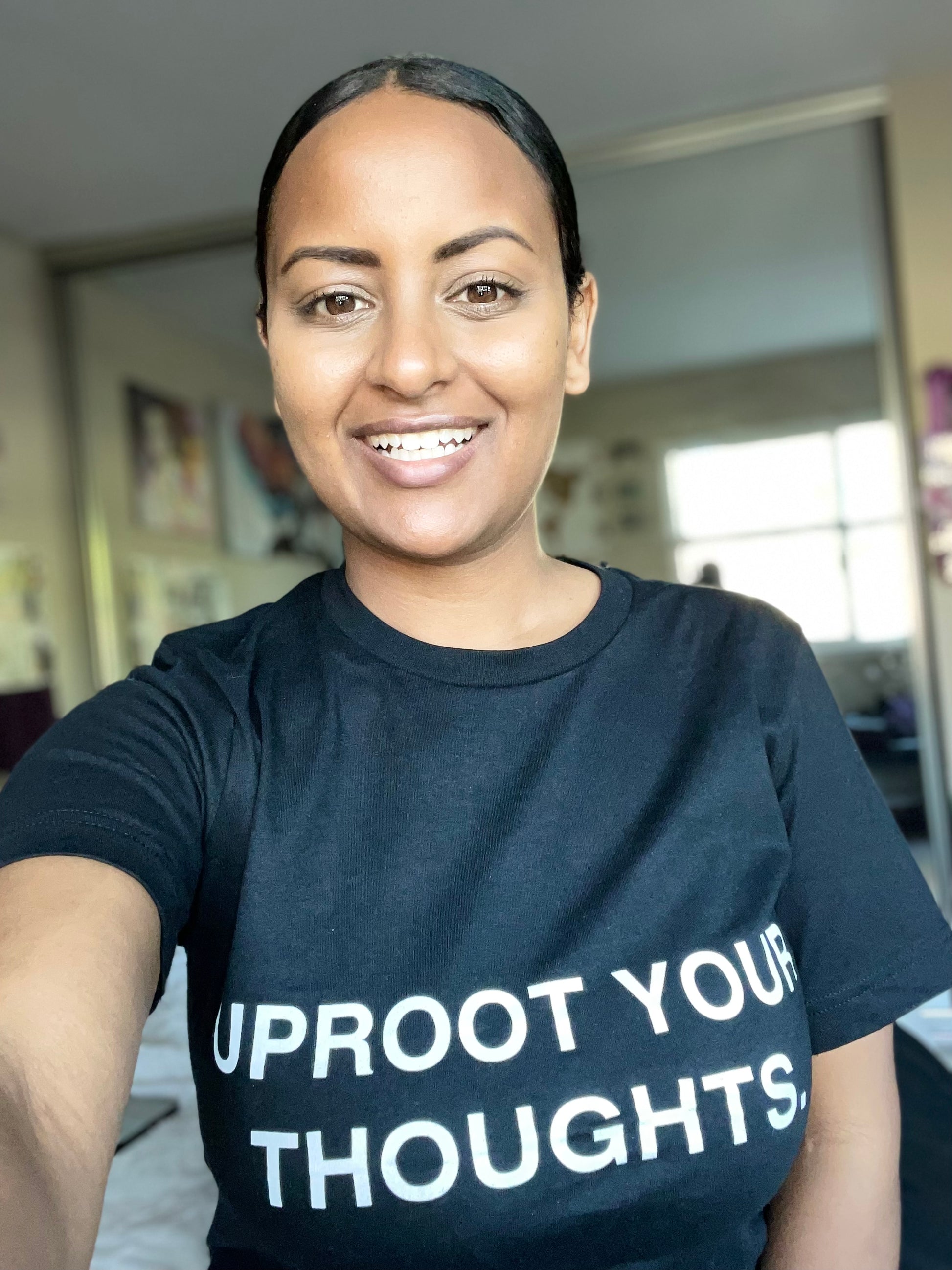 Rutha modeling the Uproot Your Thoughts t-shirt in black.