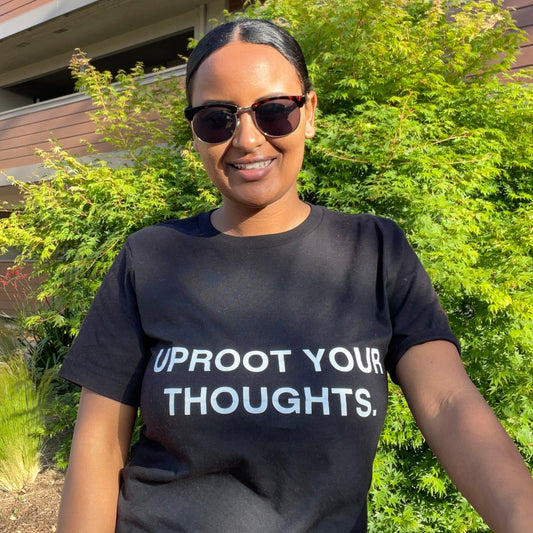 Rutha modeling the Uproot Your Thoughts t-shirt in black.